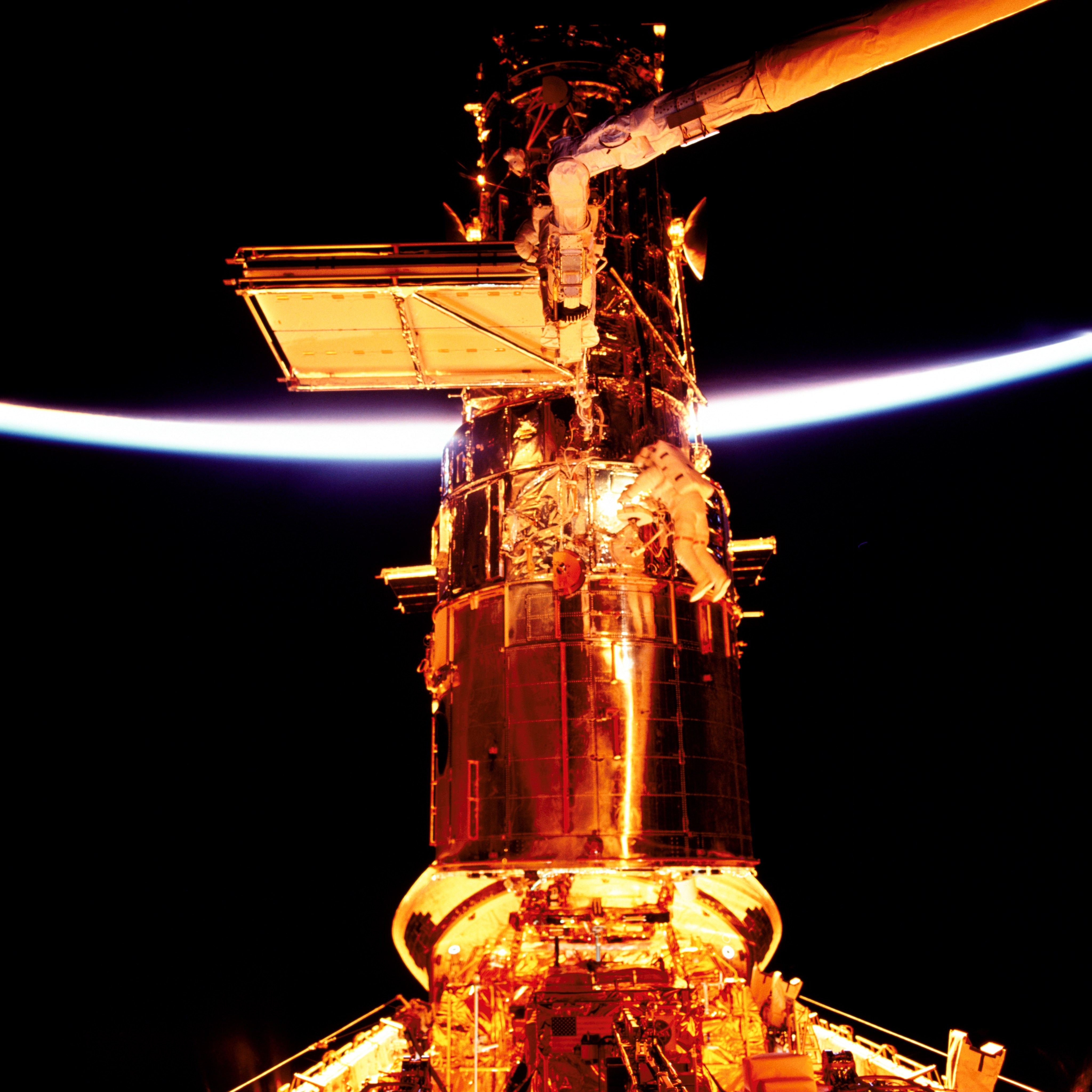 Two astronauts installing new solar arrays and electronics on Hubble.