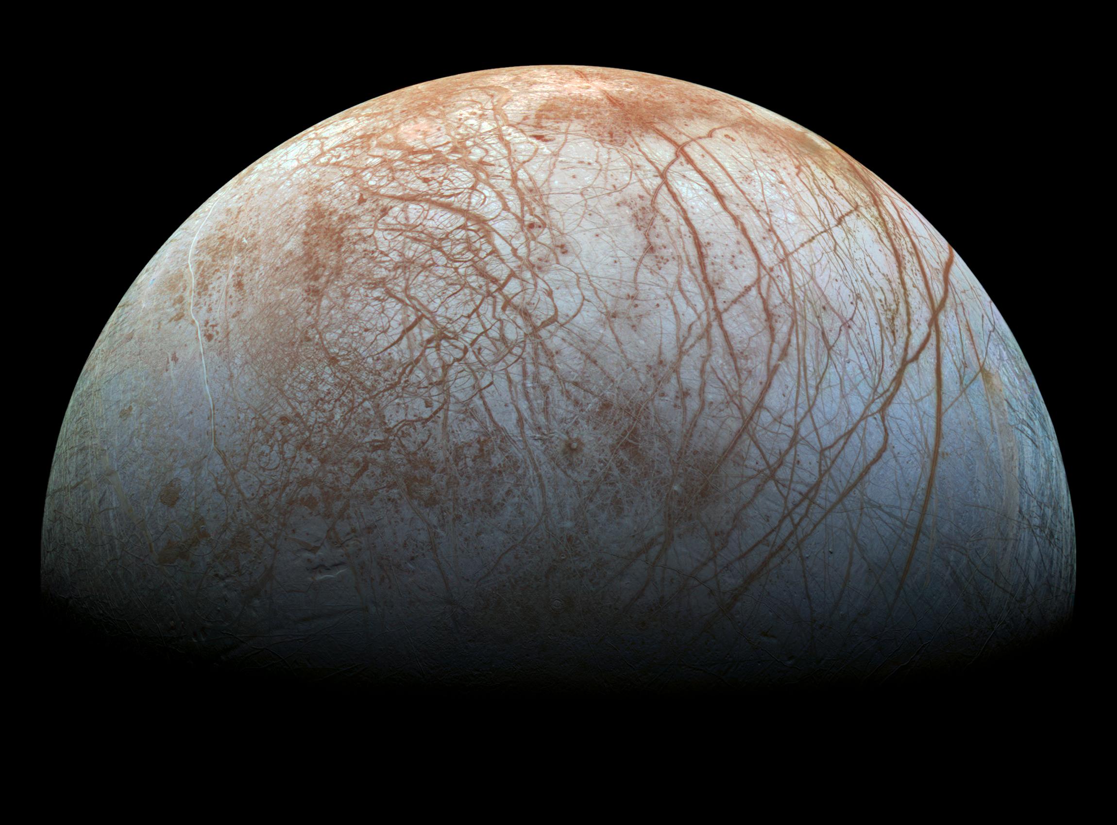 A semi-circular view of Europa, with its light blue and brown surface marked with brown lines.