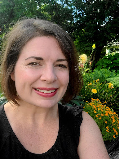 Portrait photo of a smiling woman with trees in the background.