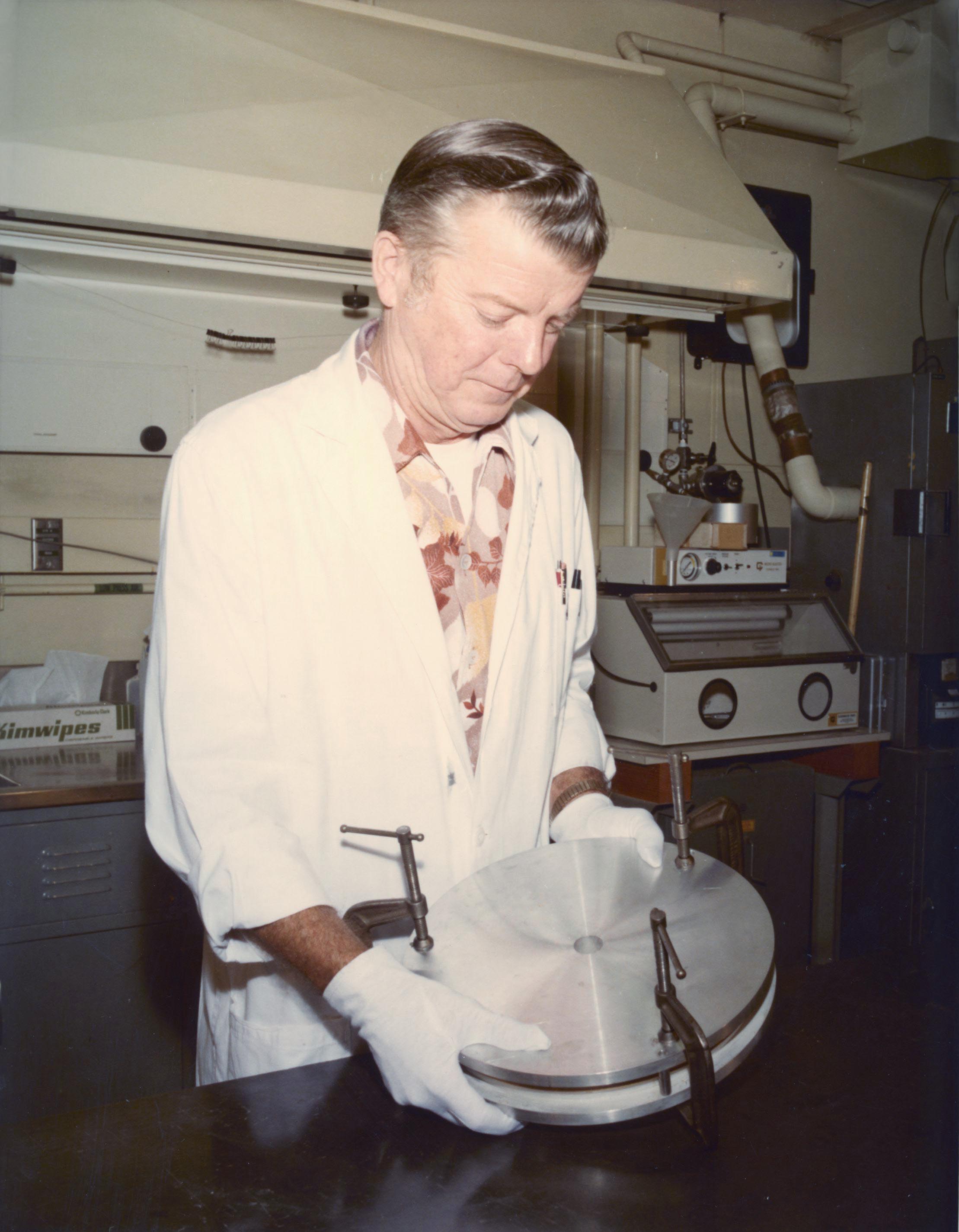 A man attaches mounting brackets to the Voyager Golden Record.