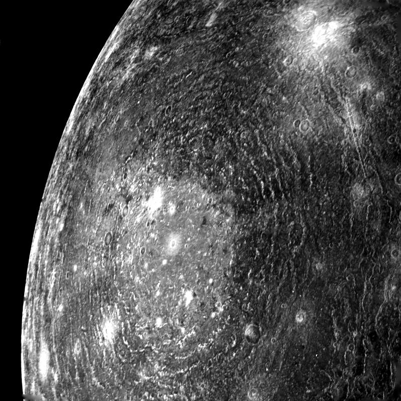 This close-up of the limb of a moon is punctuated by a large impact structure with rings radiating out across the moon.