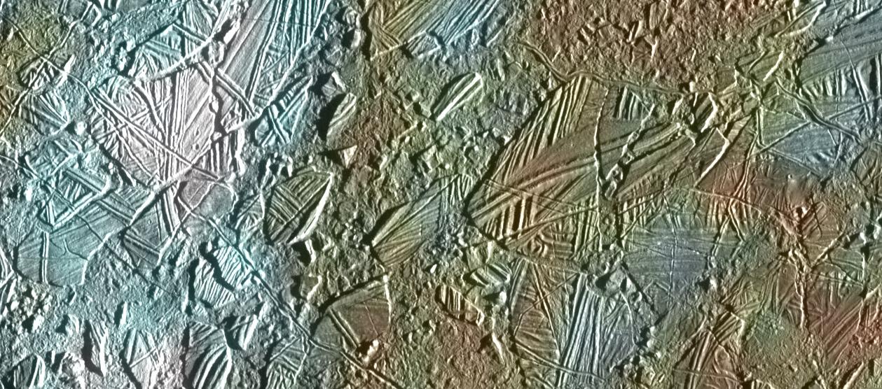 Europa's surface is streaked with reddish lines. A bright white crater is visible.