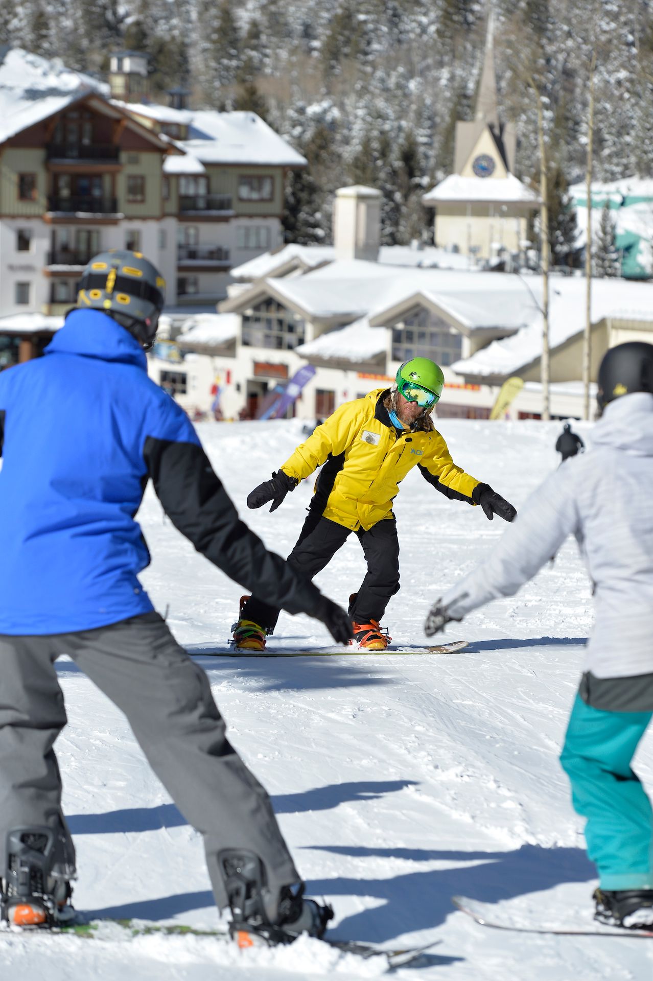 Snowboard instructor teaching a group of adult beginner snowboarders at Taos Ski Valley