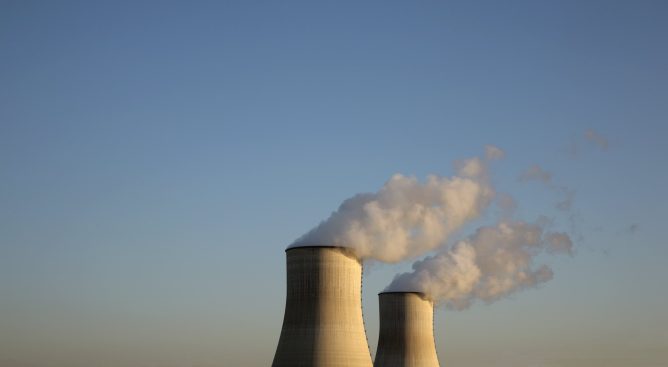 Cooling towers for a nuclear reactor stand against a blue sky.