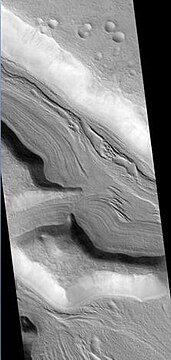 Clanis and Hypsas Valles, as seen by HiRISE. Ridges are probably due to glacial flow, so water ice is under a thin layer of rocks.