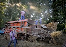 Photographie en couleurs de personnages s'affairant autour de matériels agricoles.