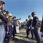 Attitude typique des Beautiful People lors d'une grande marche pour la paix en 1967 : une manifestante offre une fleur à un militaire.