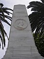 Face d'un obélisque de marbre blanc avec un médaillon représentant un profil dans une couronne de laurier