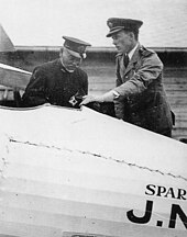 Two men standing over the interior of an airplane's cockpit