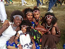 This photo represents the varieties of dressing and hairstyle of the Oromo culture. the kid sitting in front of the group dressed Guji Oromo clothes. the four girls at the back from left to right, dressed Harar, Kamise, Borena and Showa styles and all are Oromo style