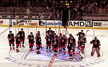 Photo des joueurs des Rangers regroupés au centre de la patinoire qui saluent la foule avec leur bâton.