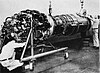 Three men work on a large jet engine suspended in a frame.