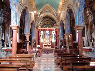 Photographie couleur de la nef d'une église richement décorée avec des colonnes en marbre rouge, murs et plafonds en mosaïque et peints en bleu.