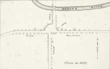 A black-and-white map, depicting buildings and roads in simple, small black outlines. The text "Utica in 1802" is at bottom right.