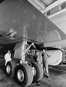 photo noir et blanc. Trois hommes autour des 4 roues de la jambe du train d'un DC-8.