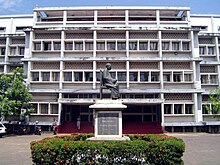 Large white building with a statue of a seated figure in front