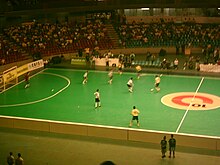 Photo des gradins d'une salle de sport où se joue une partie de futsal.