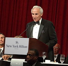 "Sandy Koufax, in formal wear, makes a speech at a podium during a dinner party."