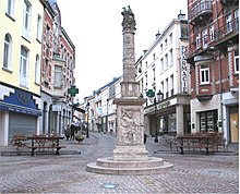 Vue d'une colonne antique surmontée d'une statue ans une rue actuelle