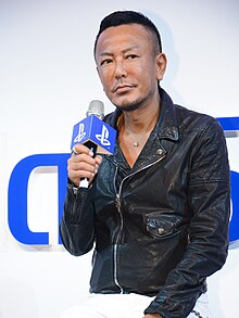 Toshihiro Nagoshi, speaking into a microphone