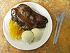 A severed sheep's head on a plate with mashed turnips and mashed potatoes