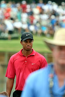 Dans une image flou, un homme au polo rouge et à la casquette noire est mise en avant par sa netteté.