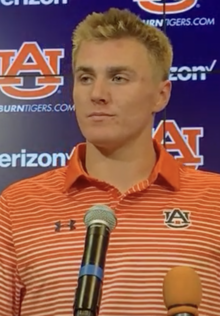 Headshot of Bo Nix, a white, clean-shaven young man with blond hair wearing a sports jersey, during a press conference.