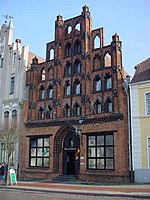 A brick building with a roof tapering dramatically toward the top via large square windows.