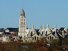 Photographie en couleurs des toits d'un grand bâtiment en pierre blanche, vu depuis le sud.