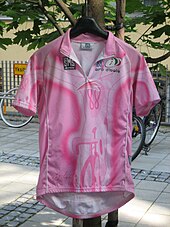 A pink jersey hung on a coat-hanger, with bikes in the background