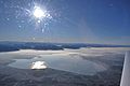 Winterliches Luftbild des Chiemsees Richtung Südwesten, im Hintergrund die Alpen; rechts im Vordergrund die Wurzel der Alz