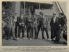 Photo noir et blanc d’une dizaine d’hommes en costume et casquette, posant pour le photographe sur le pont d’un bateau.