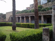 pelouse bordée d'une haie basse et d'une colonnade