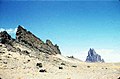 Shiprock, Mexico Mpya, Marekani, shingo ya volkeno kwa mbali, yenye lambo inayoangaza upande wake wa kusini.