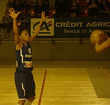 Edwige Lawson, sous le maillot de l'équipe de France, avec les bras levés, en position de défense.