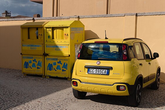 Yellow drop-off box for old clothing with blue signs and yellow car in Mantua, Italy