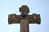 Stone cross with carvings and black circle at its center