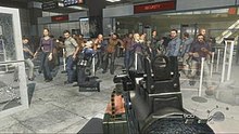 A screenshot taken from the mission. The player is holding a gun and is aiming it at a large group of civilians. Bullets can be seen coming from other gunmen offscreen.