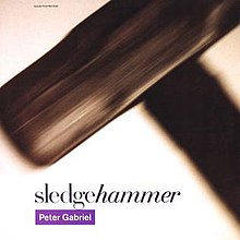 A blurred image of a sledgehammer. The text reading "hammer" in the song's title is seen italicized, while the artist's name appears in white text in a purple rectangle.