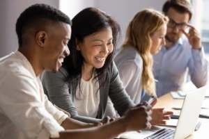 Happy mature businesswoman discussing a project on laptop with a young colleague.