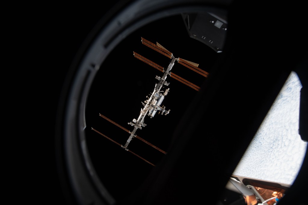 space stationn is pictured from inside a window aboard capsule during a fly around of the orbiting laboratory