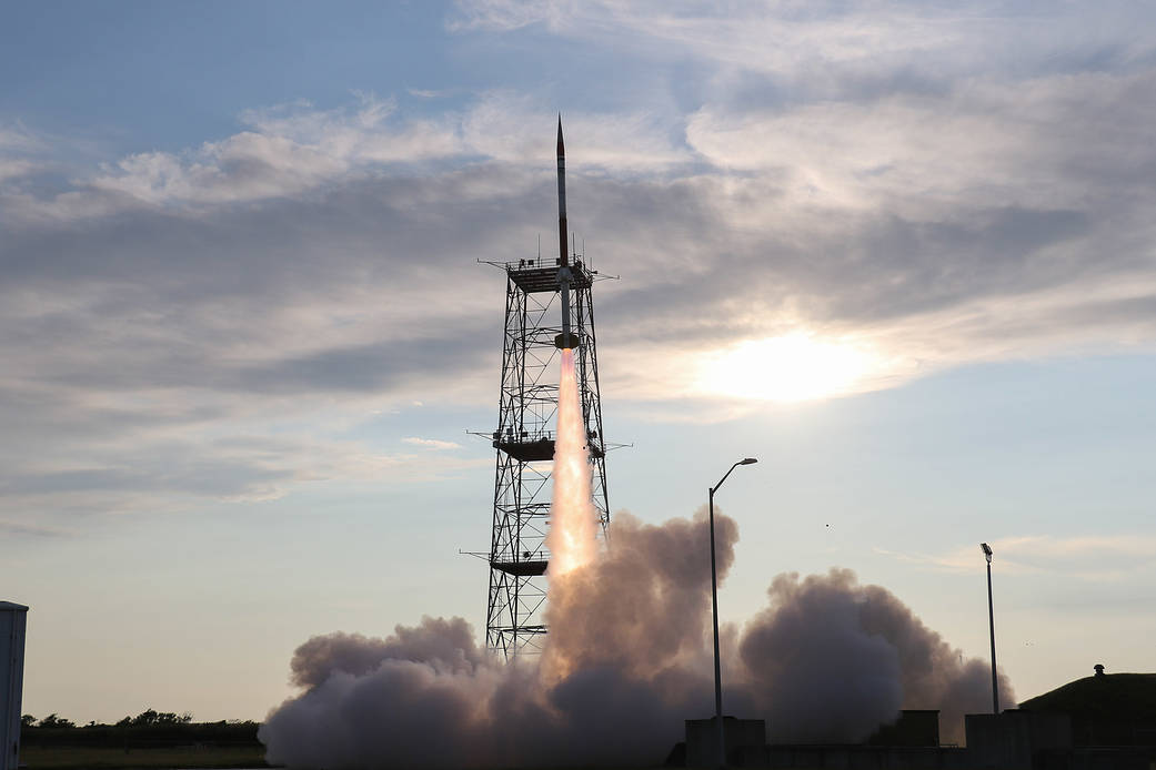 sounding rocket launching off pad with smoke plume underneath