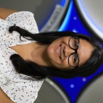 A portrait of Kennedy Space Center's Leticia Gomez with the Launch Services Program insignia in the background.