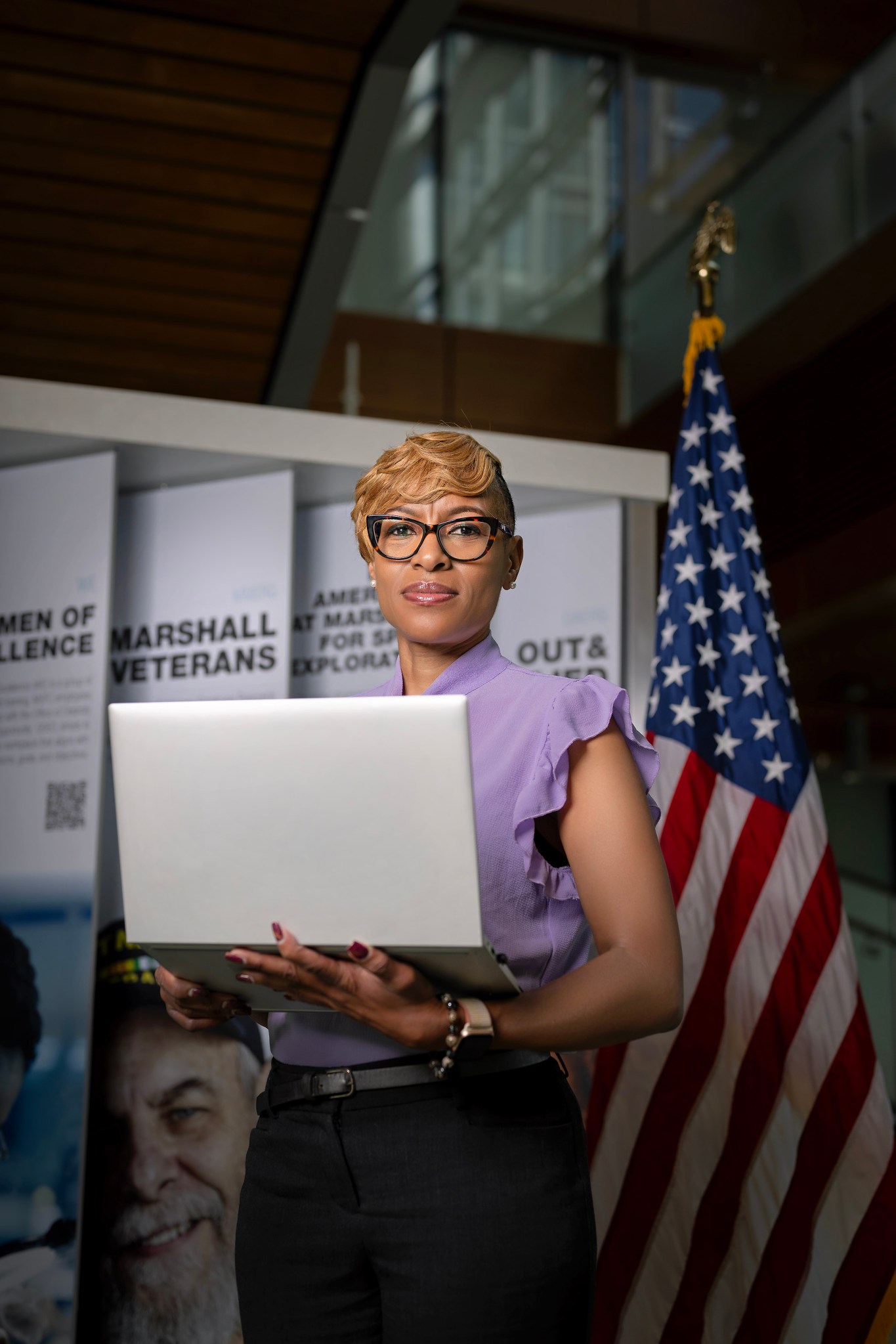 Beverly Johnson stands in front of an American Flag holding a computer.