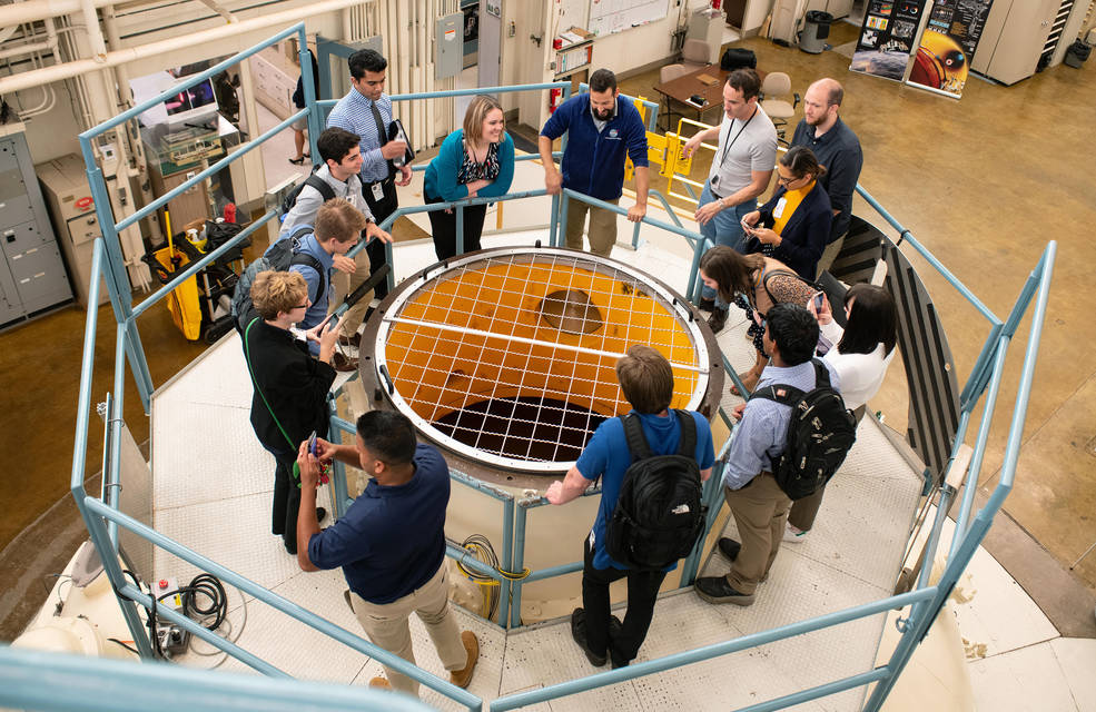 group of visitors gathered around the opening at the top of the Zero G facility