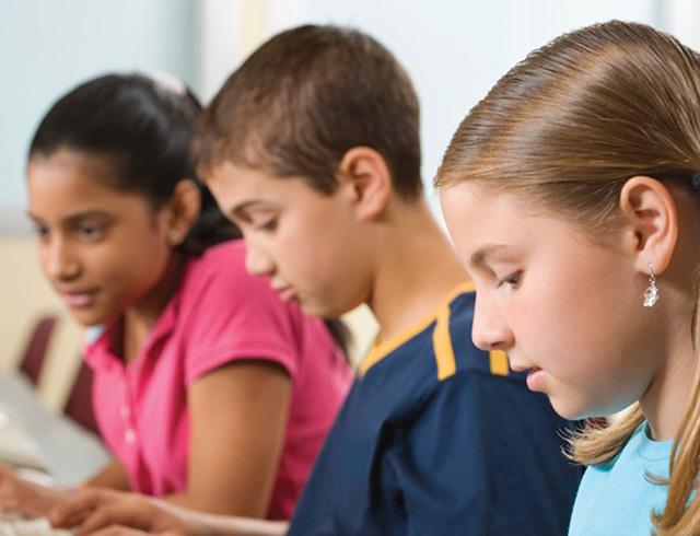 3 children working intently on computers