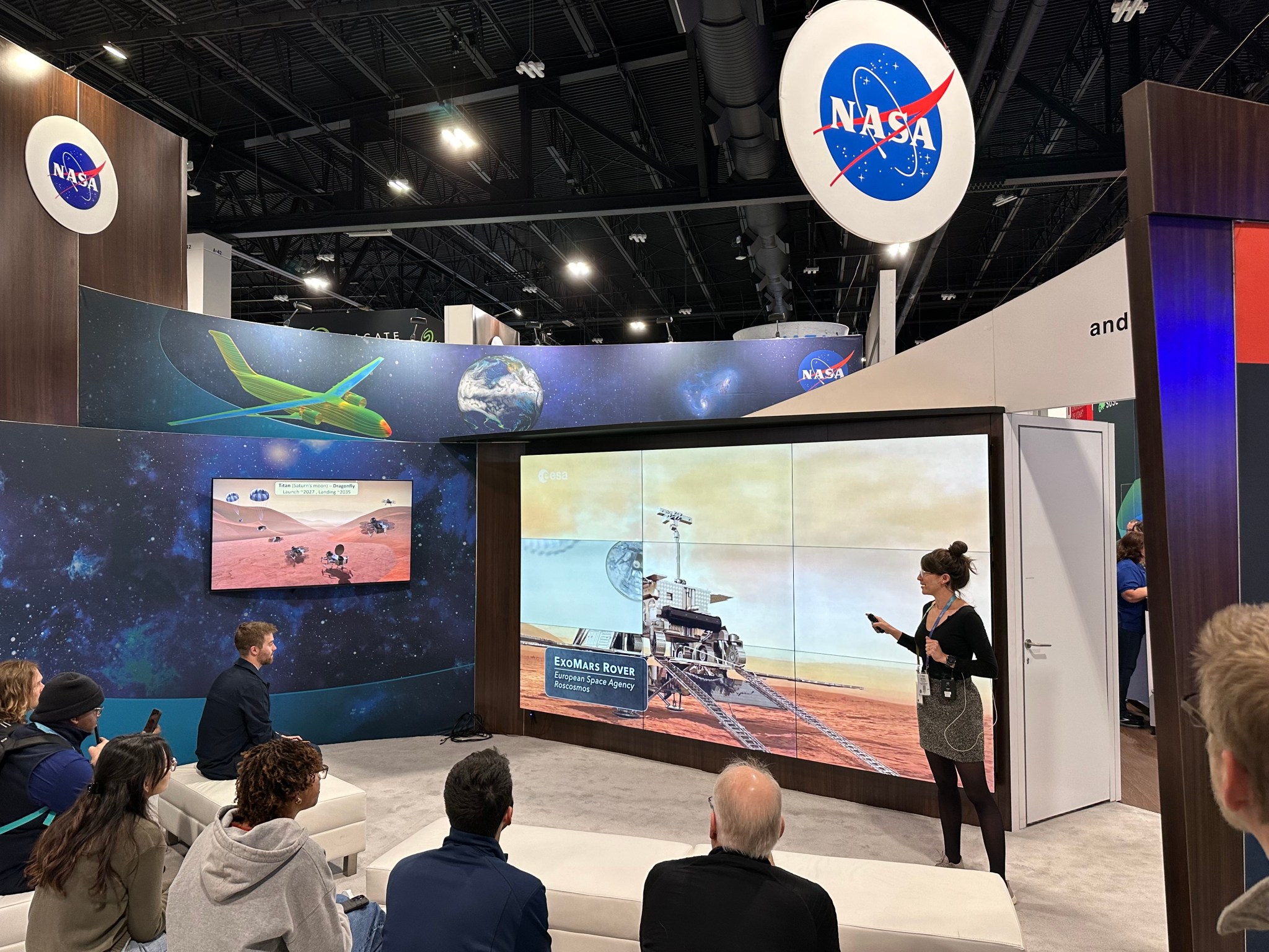 NASA data scientist Victoria Da Poian presents on the MOMA’s machine learning algorithm at the Supercomputing 2023 conference in Denver, Colorado, standing in front of a large display showing a rendering of the ExoMars Rosalind Franklin rover on Mars.