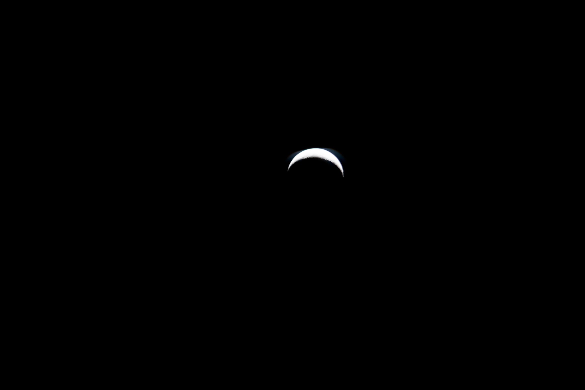 The Moon is a bright white crescent in the center of this image, surrounded by the blackness of space.